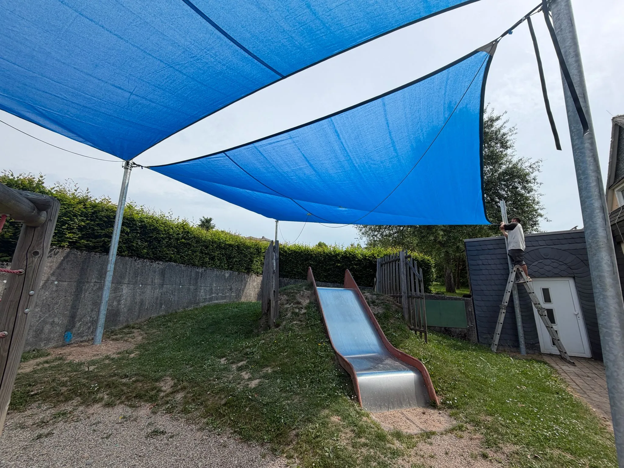 Montage eines großen Sonnensegels über einer Spielanlage durch Moshrif Spielplatzbau